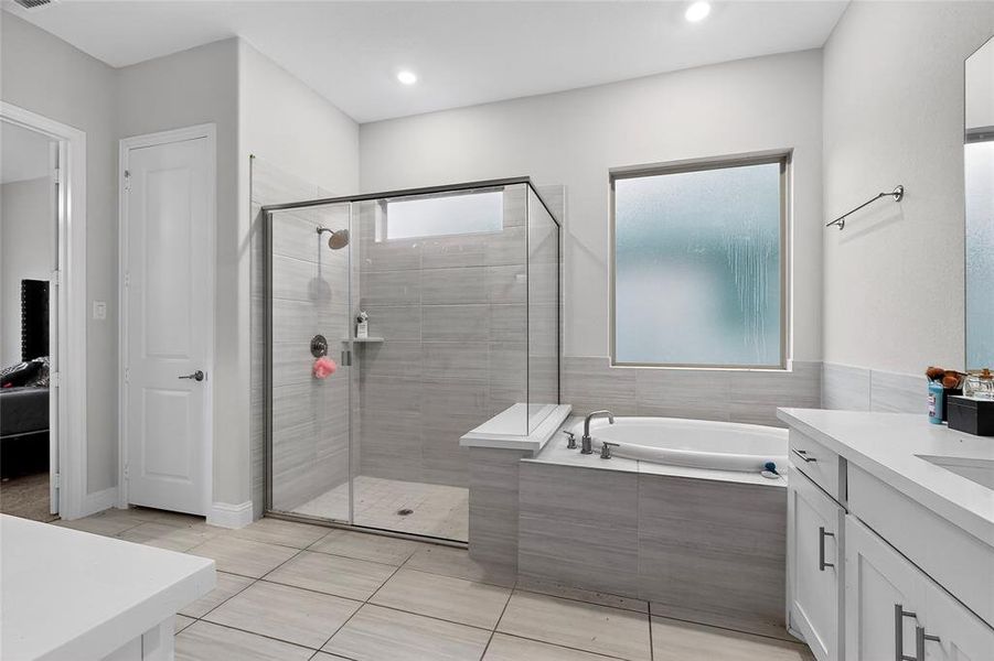 Ensuite bathroom featuring vanity, a garden tub, a shower stall, light tile patterned floors, and recessed lighting