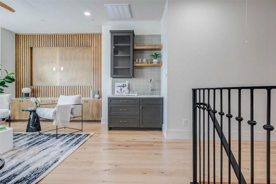 Versatile flex space featuring custom built-ins, slatted wood accent detailing, and a sleek wet bar, ideal for entertaining, relaxing, or additional living space.