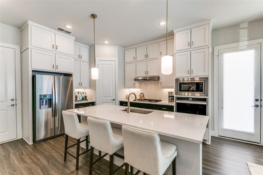 Kitchen featuring appliances with stainless steel finishes, dark hardwood / wood-style flooring, hanging light fixtures, and sink