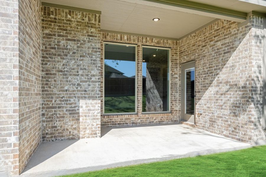 Covered back patio with concrete floor, brick exterior, large window, and back door entry Covered back patio with concrete floor, brick exterior, large window, and back door entry