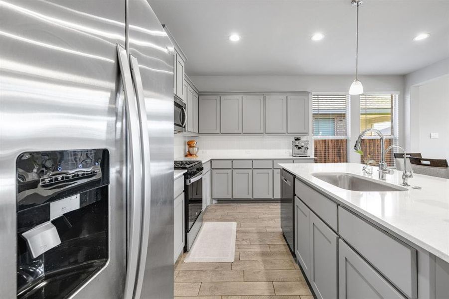 Kitchen featuring gray cabinetry, stainless steel appliances, light wood finished floors, light countertops, and recessed lighting