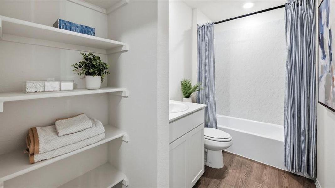 Bathroom featuring a white vanity with a rectangular sink, a toilet, and a bathtub with a shower