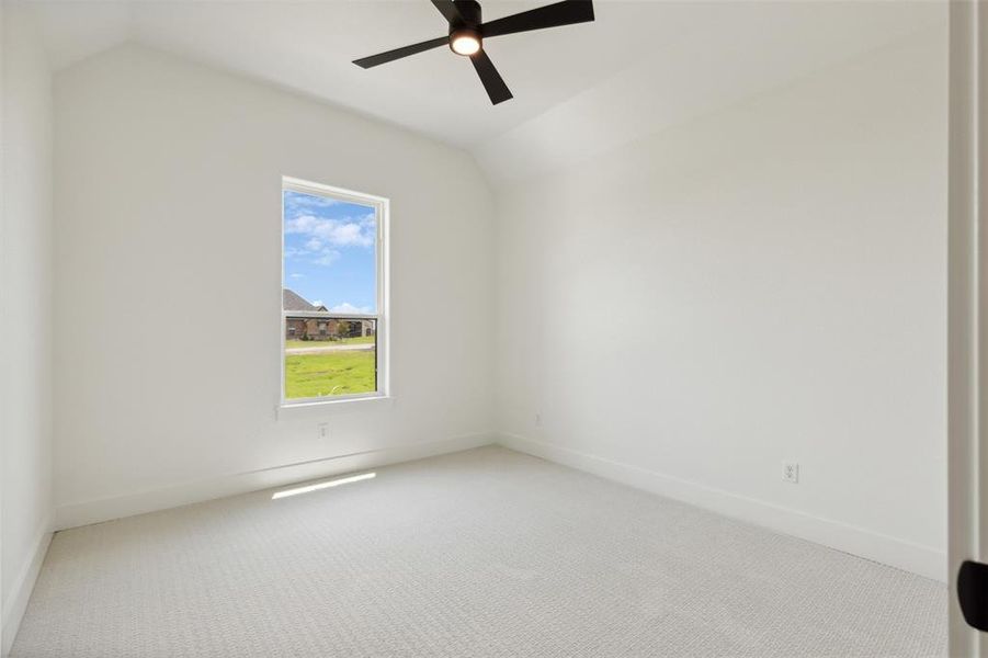 Carpeted empty room featuring lofted ceiling and ceiling fan