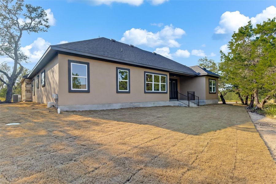 Back of property with a shingled roof, stucco siding, and a patio area Back of property with a shingled roof, stucco siding, and a patio area