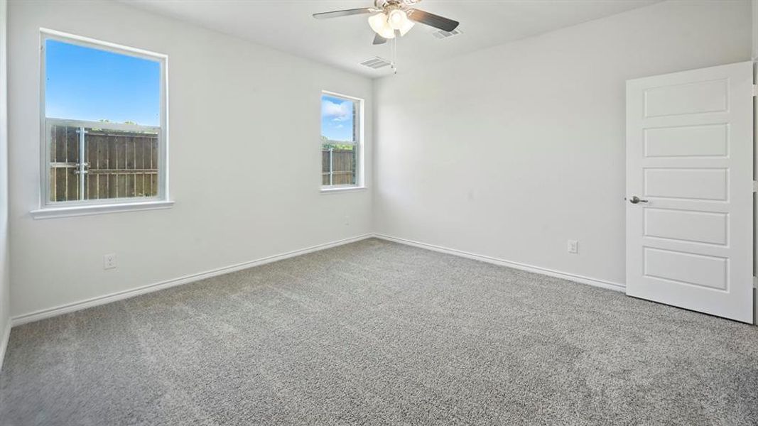 Empty room featuring carpet flooring and a ceiling fan