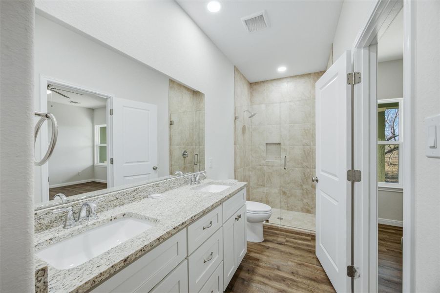 A well-appointed bath features a dual-sink vanity with granite counters and a spacious walk-in shower.