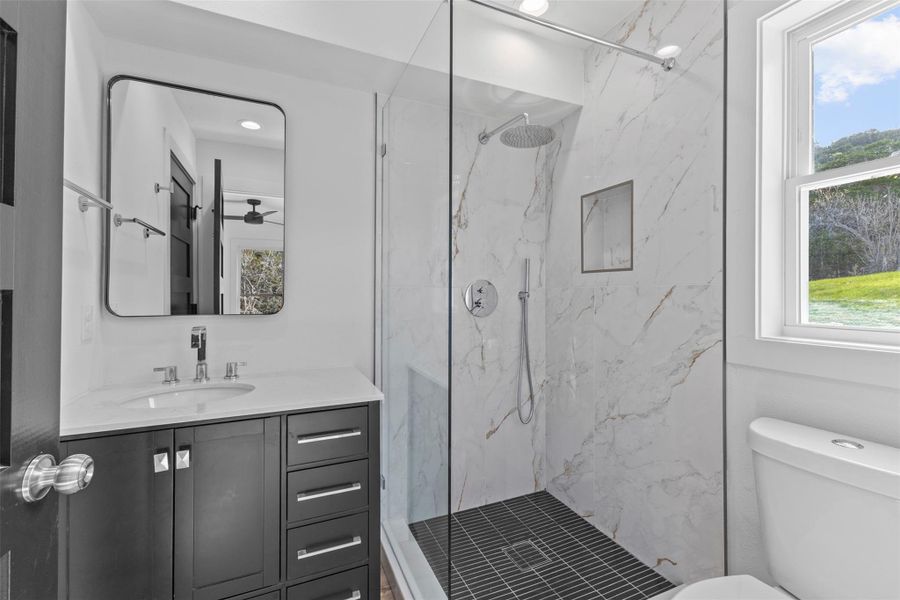 Bathroom featuring vanity and a marble finish shower