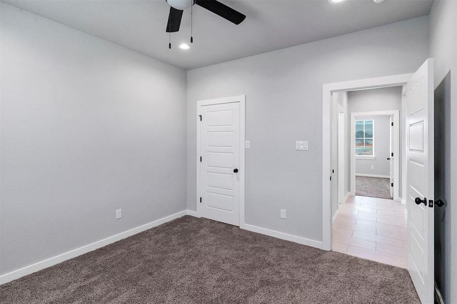 Unfurnished room featuring ceiling fan and dark colored carpet