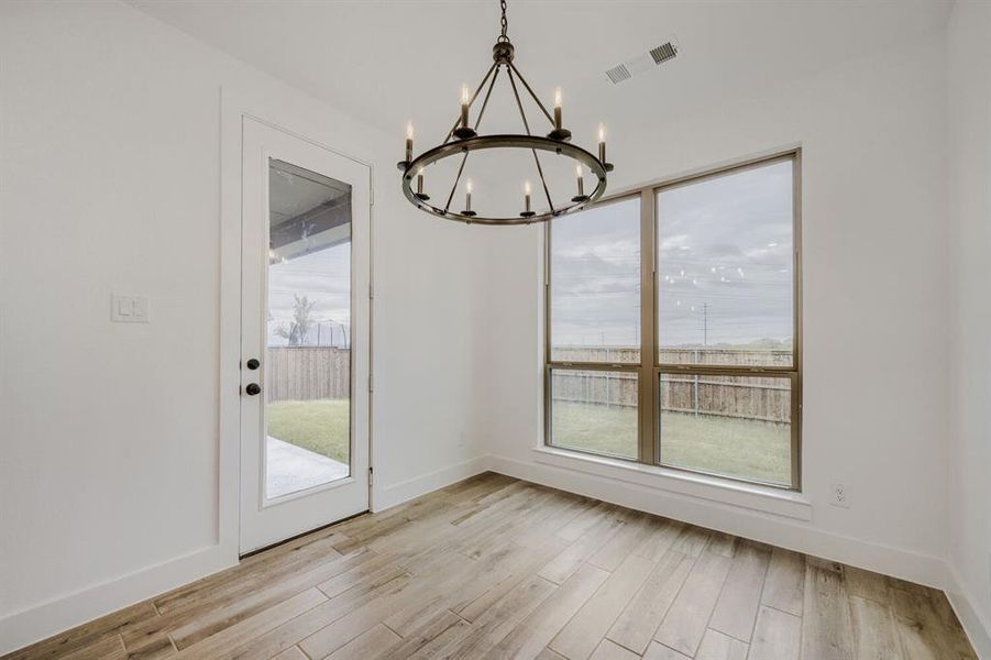 Bright interior space featuring a dark bronze chandelier, wood-finish flooring, and large picture windows