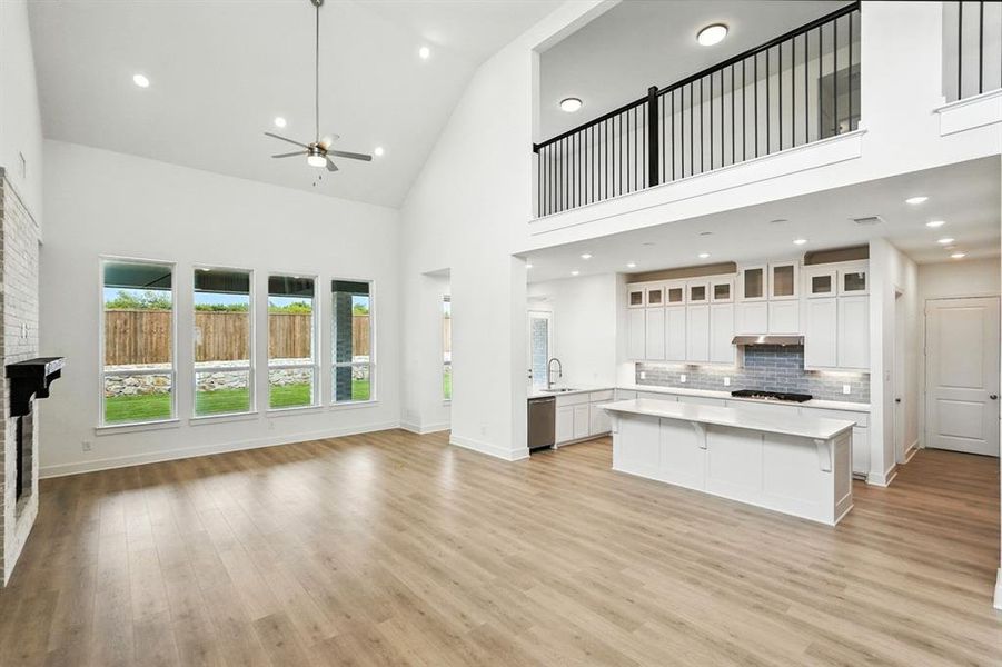 Unfurnished living room featuring high vaulted ceiling, recessed lighting, ceiling fan, a fireplace, and light wood finished floors Unfurnished living room featuring high vaulted ceiling, recessed lighting, ceiling fan, a fireplace, and light wood finished floors