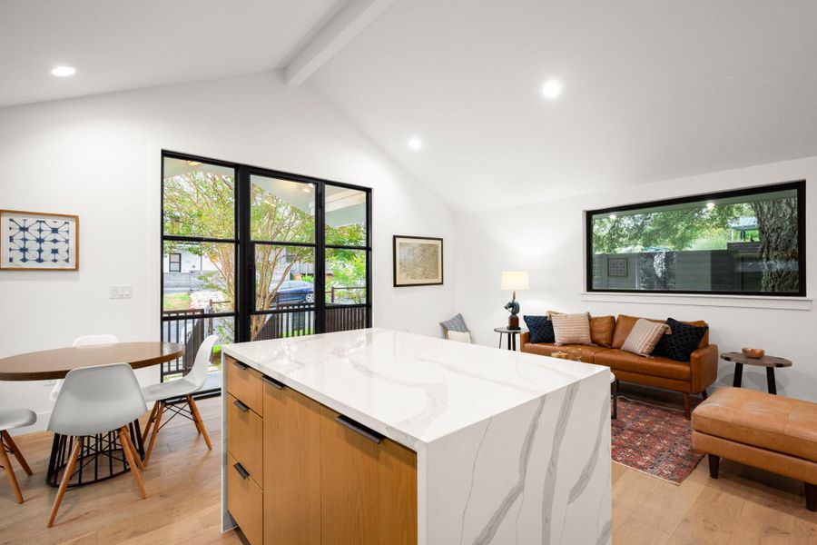 Kitchen featuring modern cabinets, recessed lighting, light stone counters, light wood-type flooring, and healthy amount of natural light