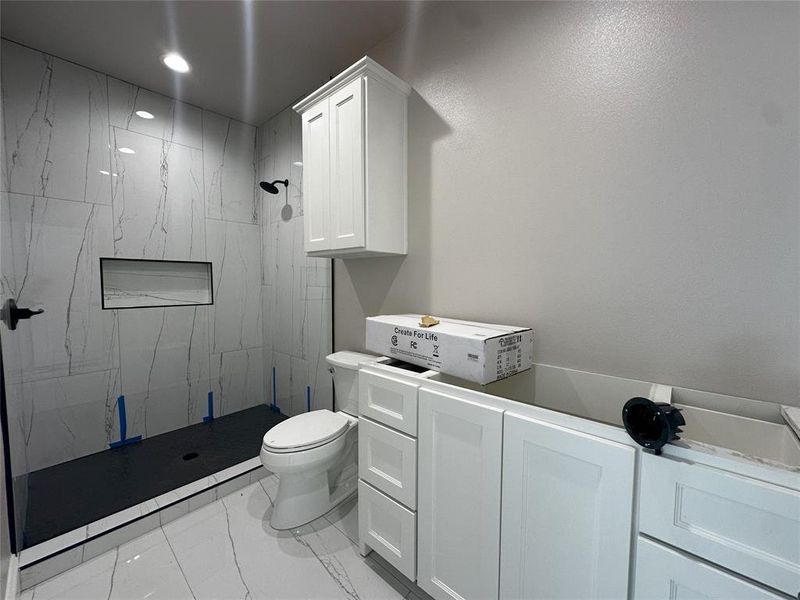 Bathroom with vanity, toilet, washer / clothes dryer, and a tile shower