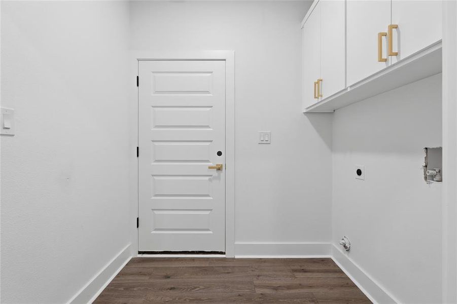 Utility room featuring white shaker-style cabinetry with gold-tone hardware, wood-finish flooring, and a five-panel interior door