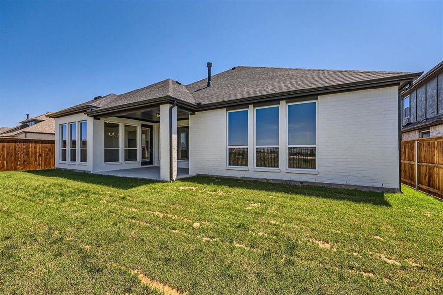 Back of property featuring a patio and a lawn