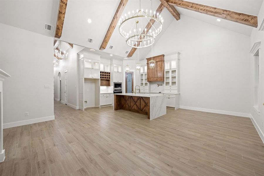Vaulted ceilings with exposed wood beams, dual chandeliers, and light wood-finish flooring Vaulted ceilings with exposed wood beams, dual chandeliers, and light wood-finish flooring
