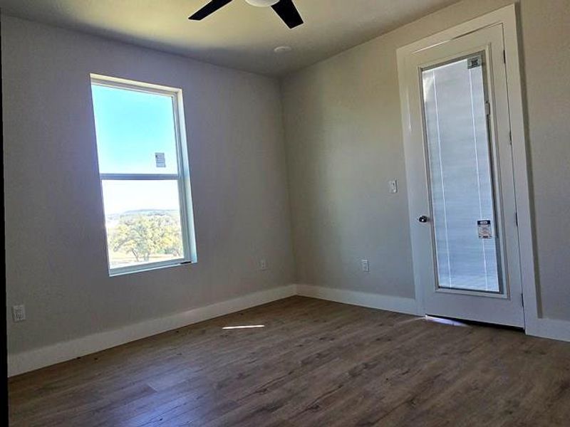 Unfurnished room featuring dark wood-style flooring and ceiling fan