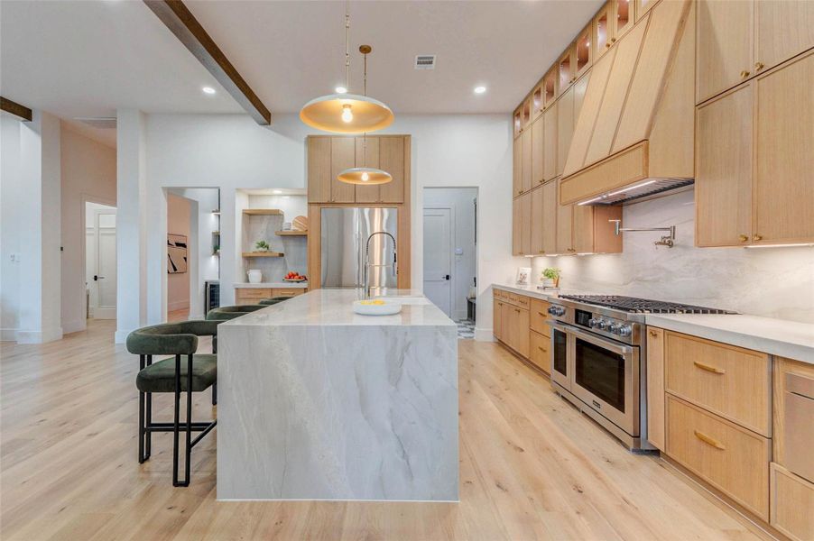 Striking kitchen with expansive island seating, ceiling-height cabinetry, professional-grade appliances, and warm wood tones throughout.