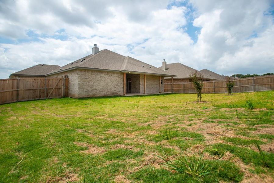 Back of property with a chimney, a fenced backyard, and brick siding Back of property with a chimney, a fenced backyard, and brick siding