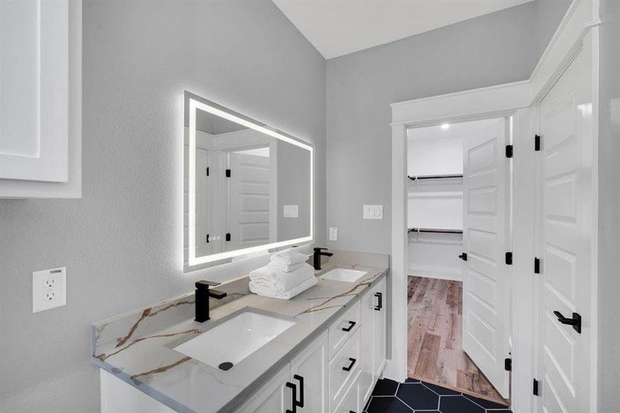 Bathroom featuring double vanity, designer tile patterned floors, and walk in closet.