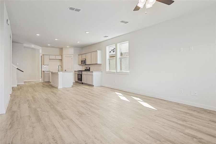 Unfurnished living room with sink, light hardwood / wood-style floors, and ceiling fan