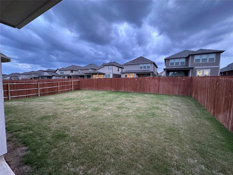 Expansive backyard featuring a fenced perimeter, a grass lawn, and a partial covered patio area Expansive backyard featuring a fenced perimeter, a grass lawn, and a partial covered patio area