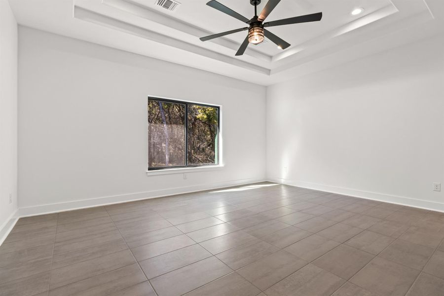 Spare room with a raised ceiling and a ceiling fan