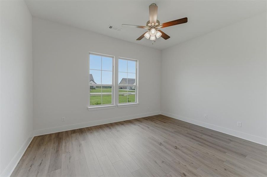 Room featuring wood-finish flooring, two window units, and a ceiling fan with integrated lighting