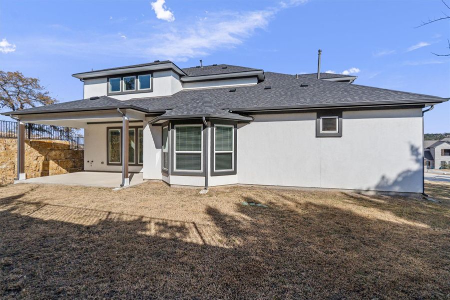 Back of property featuring a patio area, roof with shingles, and stucco siding Back of property featuring a patio area, roof with shingles, and stucco siding