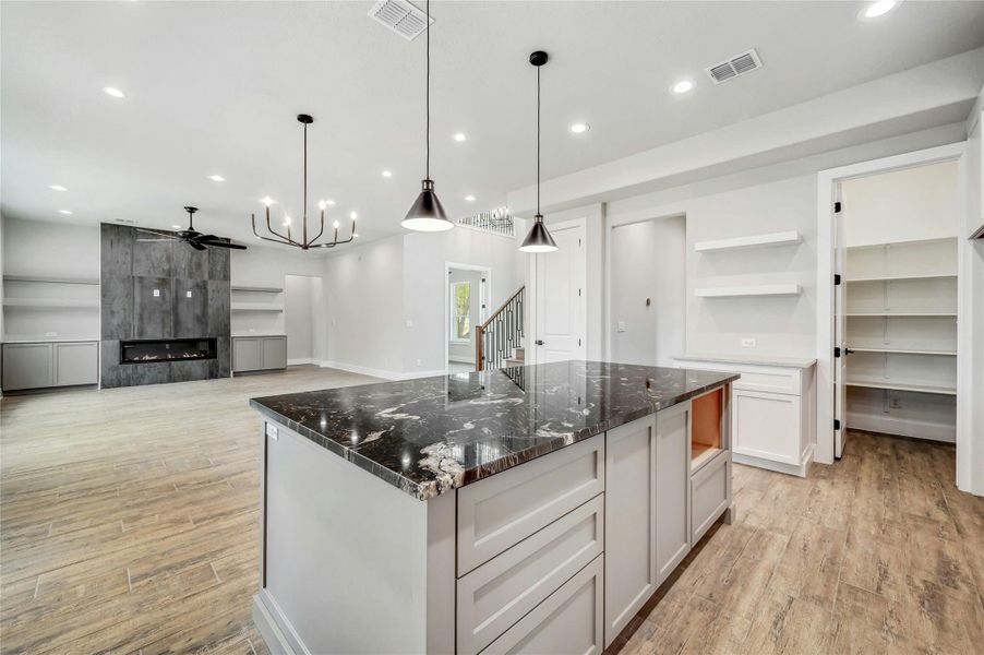 Kitchen with light wood-style flooring, visible vents, and a tiled fireplace