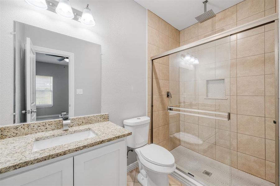 Bathroom with walk in shower, vanity, toilet, and ceiling fan