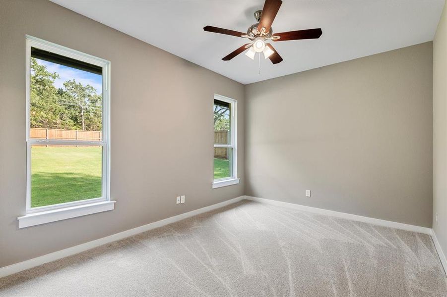 Carpeted spare room featuring plenty of natural light and ceiling fan Carpeted spare room featuring plenty of natural light and ceiling fan