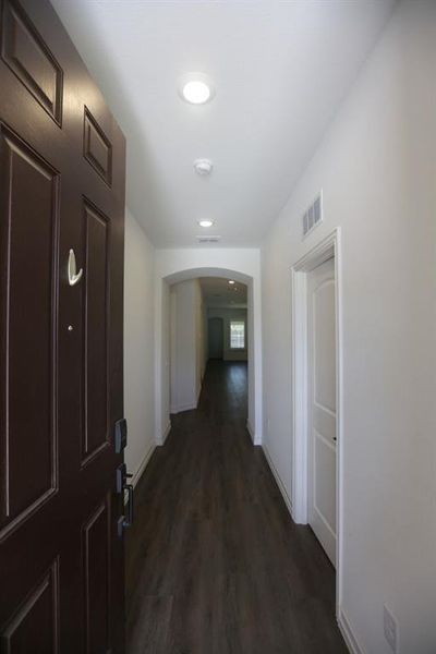 Entryway featuring a dark wood-finish door with panel detailing, dark wood-finish flooring, white walls, and recessed lighting