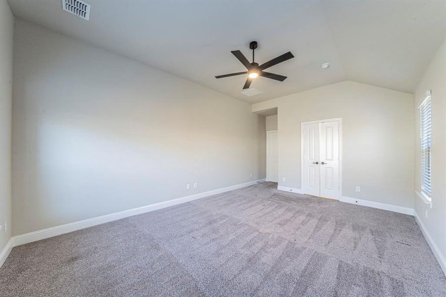 Spacious room featuring vaulted ceilings, neutral-toned walls, and plush gray carpeting