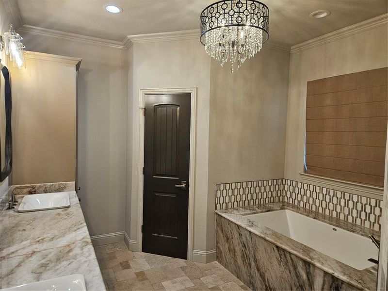 Bathroom featuring ornamental molding, vanity, and a relaxing tiled tub