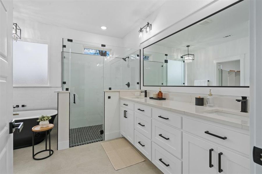 Full bath featuring a stall shower, a freestanding tub, a sink, and double vanity