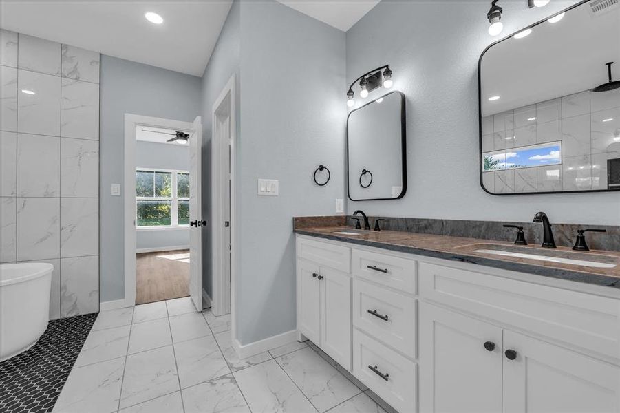 Full bathroom with a soaking tub, double vanity, light marble finish flooring, a tile shower, and a ceiling fan Full bathroom with a soaking tub, double vanity, light marble finish flooring, a tile shower, and a ceiling fan