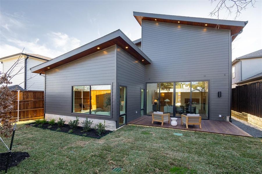 Rear view of property featuring a wooden deck and a yard