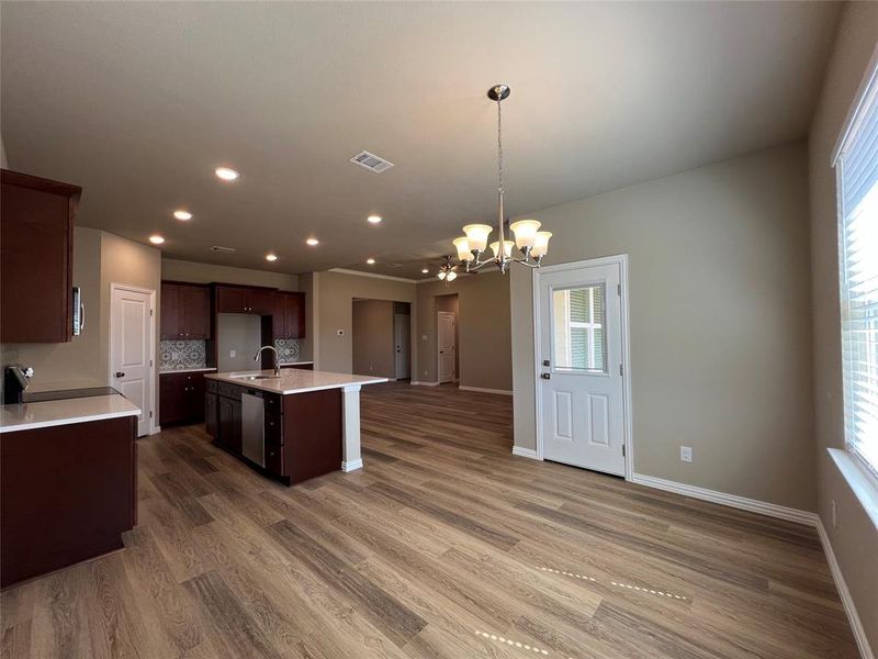 Kitchen featuring a notable chandelier, pendant lighting, an island with sink, and a wealth of natural light