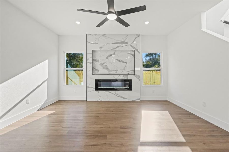 Unfurnished living room featuring plenty of natural light, light wood-style flooring, a ceiling fan, and recessed lighting