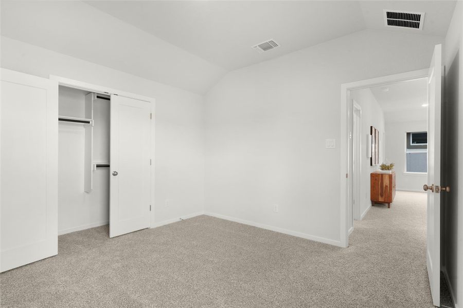 Unfurnished bedroom with vaulted ceiling, carpet floors, and a closet