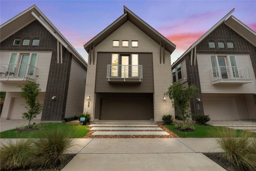 This stunning two-story home features a sleek exterior, soft neutral tones, and a charming balcony. The landscaped front yard and driveway leading to the garage add both convenience and eye-catching curb appeal.