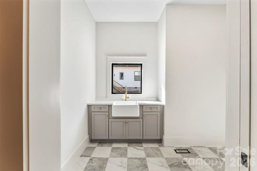 The drop zone flows into a massive laundry room with abundant cabinetry and a farmhouse sink that makes even daily routines feel refined.