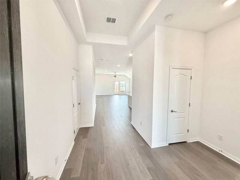 Hallway featuring light wood finished floors, a raised ceiling, and recessed lighting