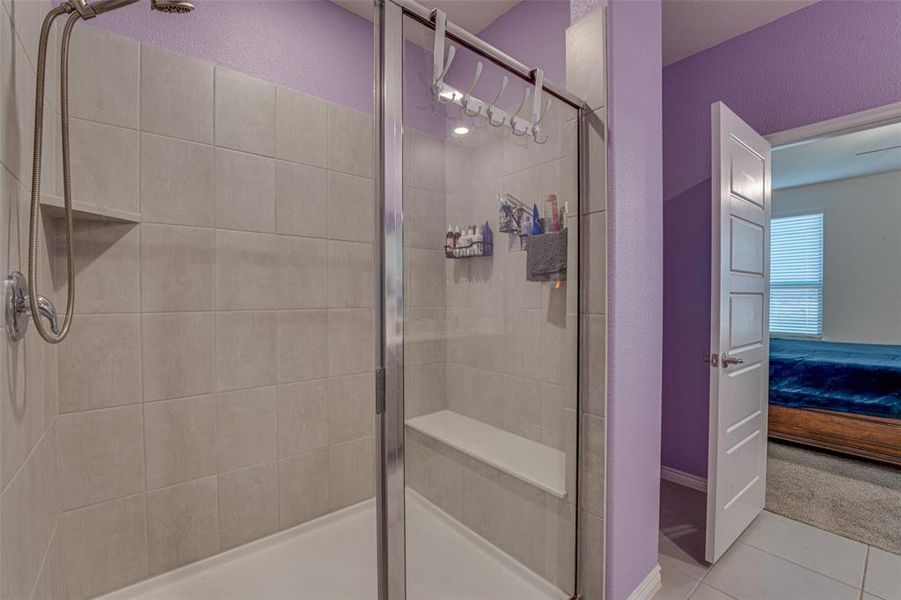 Full bathroom with ensuite bath, tile patterned flooring, a stall shower, carpet, and a textured wall