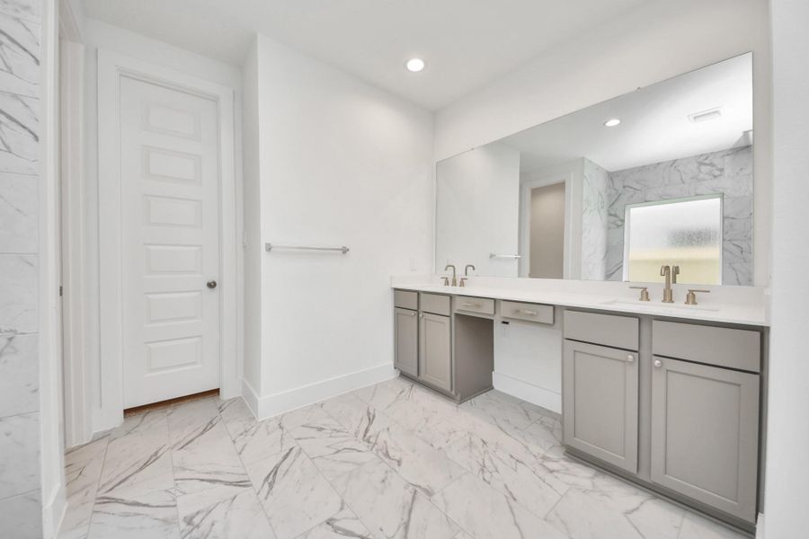 Escape to a spa-like oasis in this primary bathroom. Enjoy a walk-in shower with tile surround, a separate garden tub with custom detailing, and an elegant vanity featuring light countertops, modern hardware, and beautiful recessed lights. Experience luxury and relaxation in every detail.