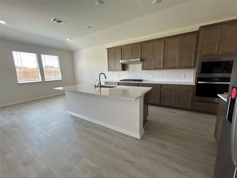 Kitchen featuring backsplash, stainless steel oven, recessed lighting, light wood finished floors, and a kitchen island with sink Kitchen featuring backsplash, stainless steel oven, recessed lighting, light wood finished floors, and a kitchen island with sink