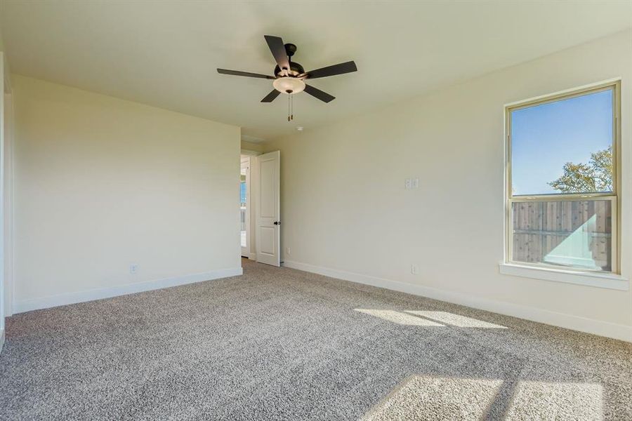 Carpeted spare room featuring baseboards and a ceiling fan