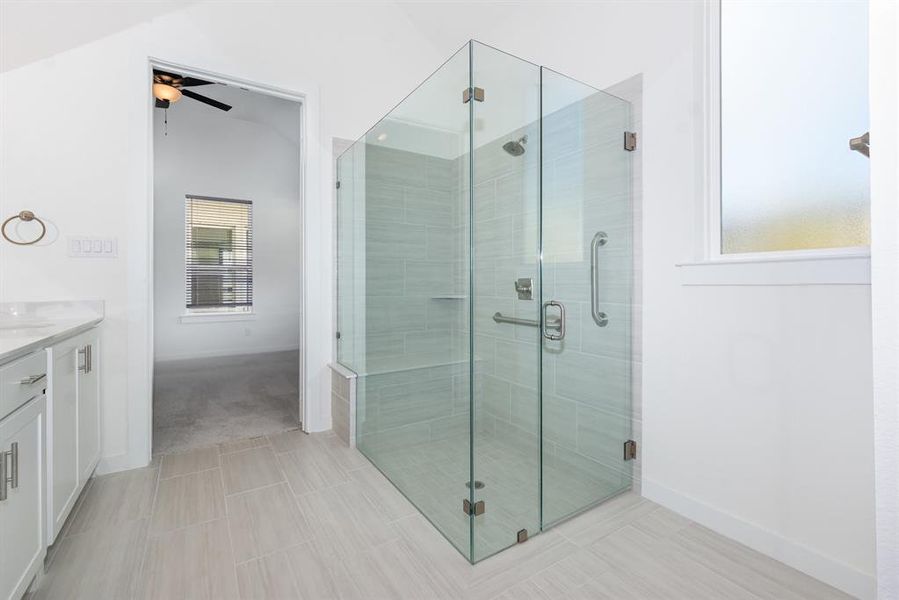 Full bath with vanity, a stall shower, light tile patterned floors, lofted ceiling, and ceiling fan Full bath with vanity, a stall shower, light tile patterned floors, lofted ceiling, and ceiling fan