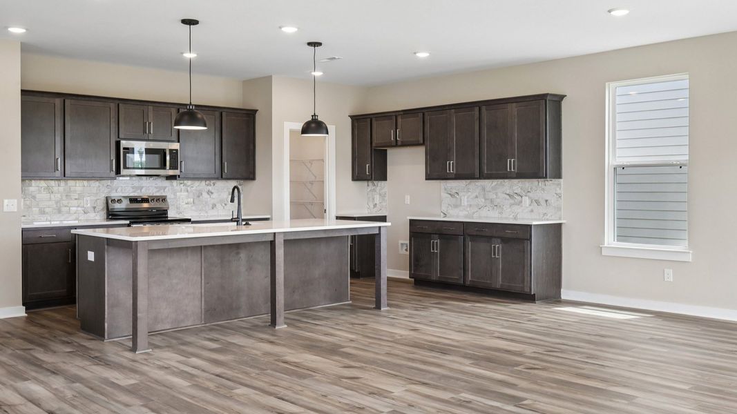 Kitchen with dark cabinetry, quartz countertops, and tile backsplash Kitchen with dark cabinetry, quartz countertops, and tile backsplash