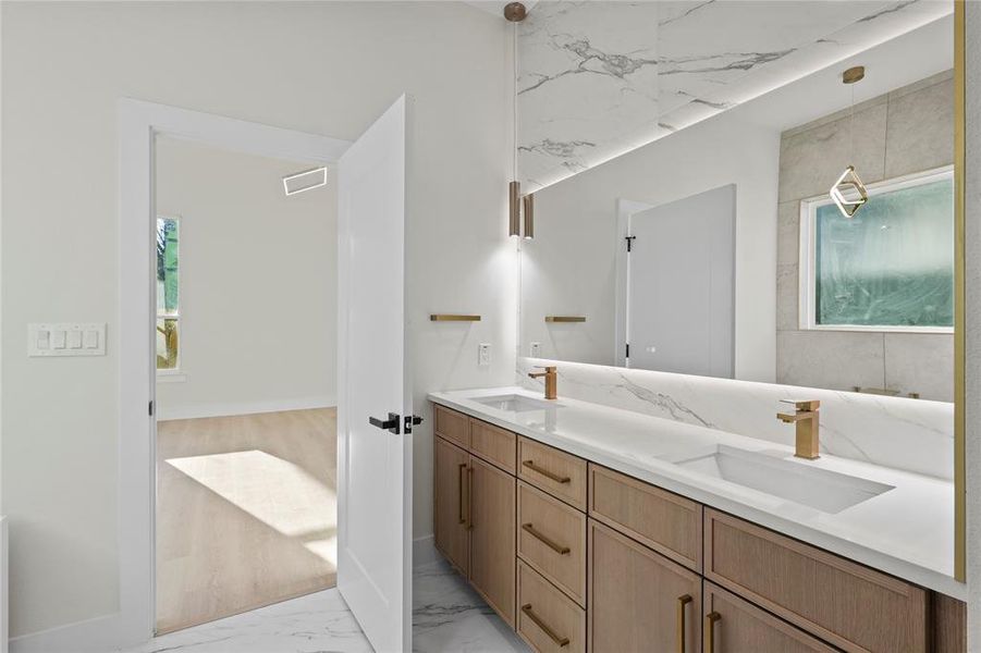 Bathroom featuring double vanity, marble finish floor, visible vents, and a sink